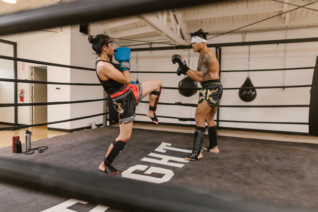Adult men and women engaged in Muay Thai training session in a boxing ring, showcasing skill and determination.